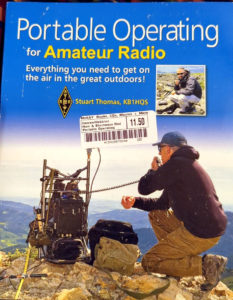 Front cover of Portable Operating for Amateur Radio by  Stuart Thomas KB1HQS.  The cover features a man kneeling on a mountain top summit holding a microphone connected to a radio on a metal frame backpack.