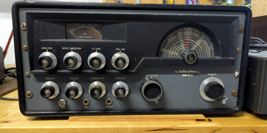 An old Hallicrafters HT-32 amateur radio transmitter sitting on a workbench